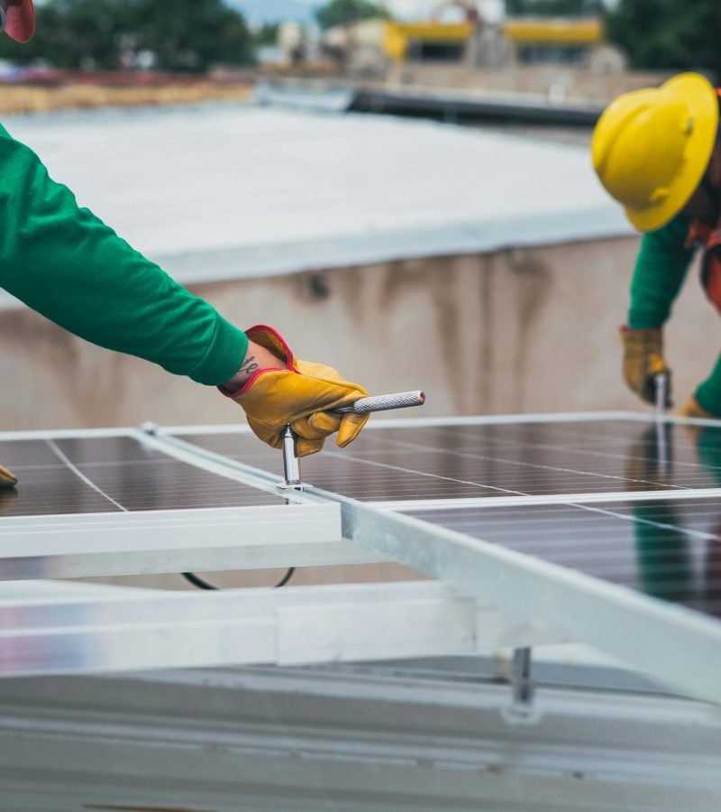 Workers secure solar panels on a rooftop, advancing renewable energy.